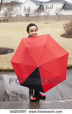Mixed race boy playing with umbrella in rain View Large Photo Image Stock Image - Mixed race boy playing with umbrella in rain. Fotosearch