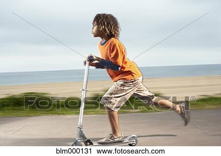 Mixed Race boy riding foot-powered scooter View Large Photo Image Stock Image - Mixed Race boy riding foot-powered scooter. Fotosearch