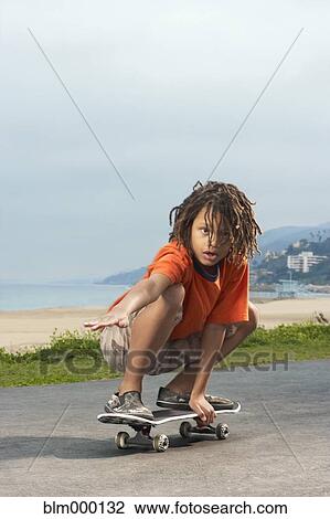 Stock Image - Mixed Race boy riding skateboard. Fotosearch