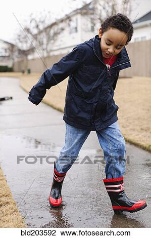 Mixed race boy splashing in rainboots View Large Photo Image Stock Image - Mixed race boy splashing in rainboots. Fotosearch