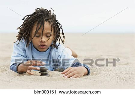 Mixed Race boy stacking stones on sand View Large Photo Image Stock Image - Mixed Race boy stacking stones on sand. Fotosearch