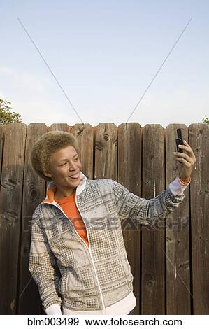 Stock Photo - Mixed race boy taking self-portrait with cell phone. Fotosearch