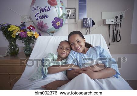 Stock Photograph - Mixed Race brother and sister in hospital bed. Fotosearch