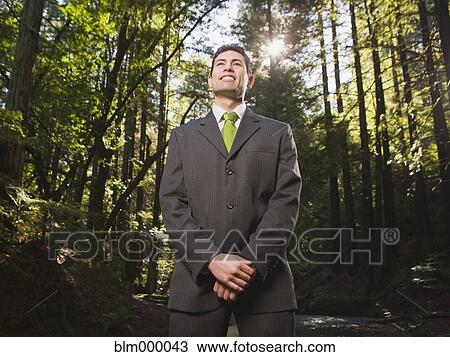 Stock Image - Mixed Race businessman in woods. Fotosearch