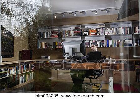 Stock Photography - Mixed race businessman sitting at desk. Fotosearch