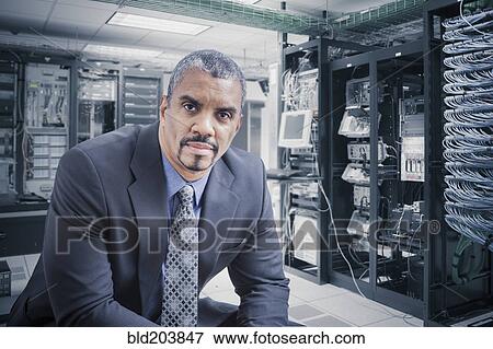 Stock Photo - Mixed race businessman sitting in server room. Fotosearch