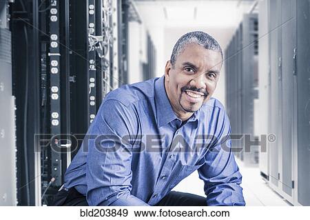 Stock Photo - Mixed race businessman sitting in server room. Fotosearch