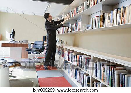 Mixed race businessman taking book from shelf View Large Photo Image Stock Photo - Mixed race businessman taking book from shelf. Fotosearch