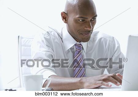 Mixed race businessman using laptop at desk View Large Photo Image Stock Image - Mixed race businessman using laptop at desk. Fotosearch