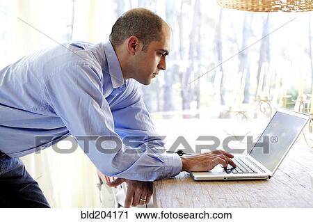 Stock Image - Mixed race businessman using laptop in office. Fotosearch