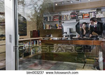 Stock Photo - Mixed race businesswoman sitting at desk with co-worker. Fotosearch