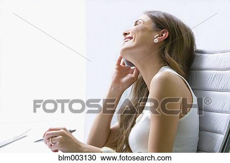 Mixed race businesswoman talking on cell phone at desk View Large Photo Image Stock Image - Mixed race businesswoman talking on cell phone at desk. Fotosearch