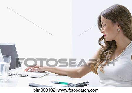 Stock Image - Mixed race businesswoman working at desk. Fotosearch