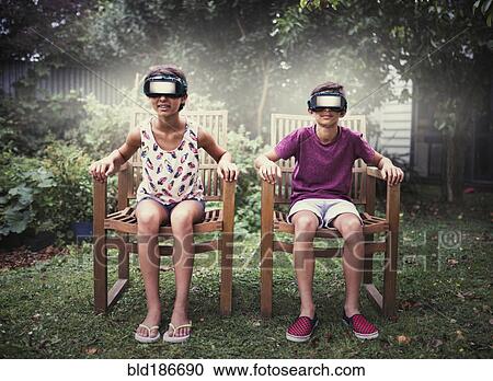 Stock Image - Mixed race children watching virtual reality screens. Fotosearch