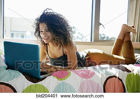 Stock Image - Mixed race college student using laptop in dorm. Fotosearch