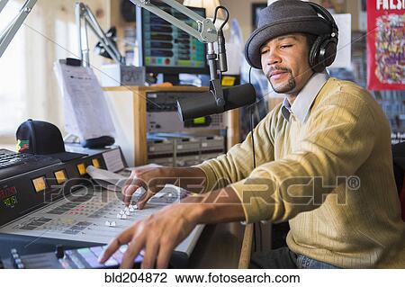 Stock Image - Mixed race disc jockey using control panel in studio. Fotosearch