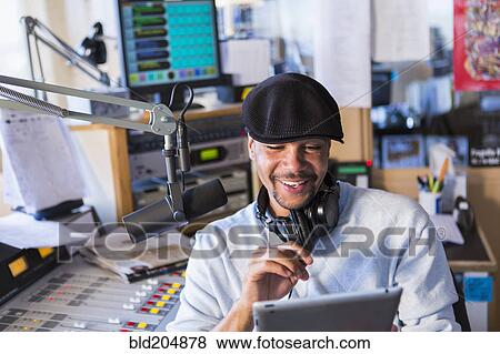 Stock Photo - Mixed race disc jockey using tablet computer in studio. Fotosearch