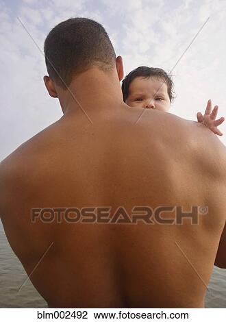 Stock Image - Mixed Race father holding baby. Fotosearch