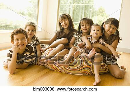 Stock Photo - Mixed race friends sitting on beanbag chair. Fotosearch