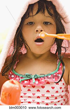 Stock Image - Mixed race girl blowing bubbles. Fotosearch