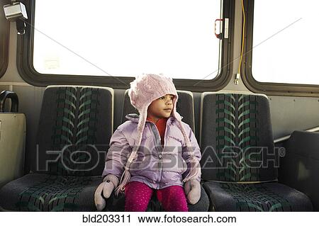 Stock Image - Mixed race girl in hat and gloves riding bus. Fotosearch