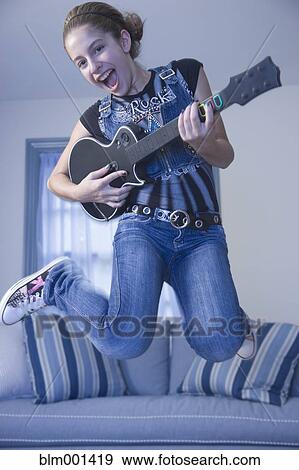 Mixed race girl jumping in livingroom with guitar View Large Photo Image Stock Photo - Mixed race girl jumping in livingroom with guitar. Fotosearch