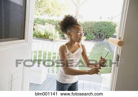 Stock Image - Mixed race girl painting doorway. Fotosearch