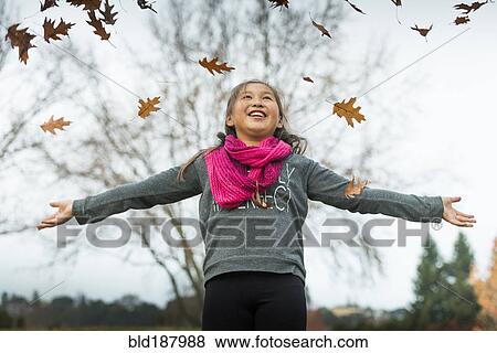 Stock Photo - Mixed race girl playing in autumn leaves. Fotosearch