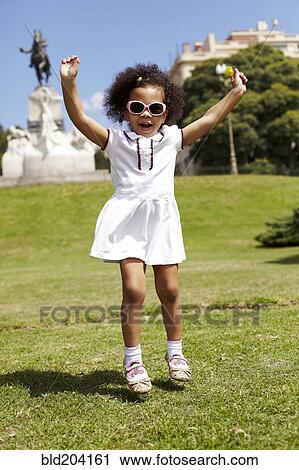 Stock Image - Mixed race girl playing in park. Fotosearch