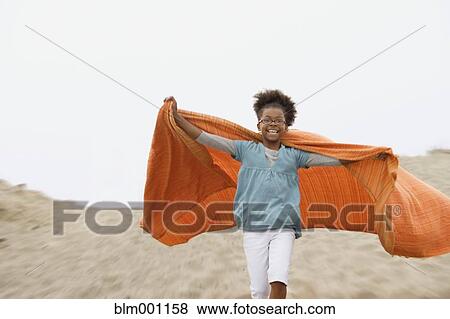 Mixed race girl playing with blanket at beach View Large Photo Image Stock Photo - Mixed race girl playing with blanket at beach. Fotosearch