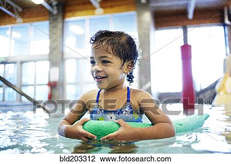 Stock Image - Mixed race girl using floater in swimming pool. Fotosearch