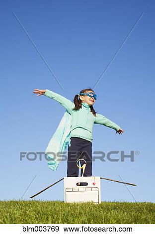 Stock Photo - Mixed race girl wearing cape and standing in box. Fotosearch