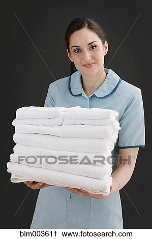 Mixed race maid holding stack of towels View Large Photo Image Stock Image - Mixed race maid holding stack of towels. Fotosearch