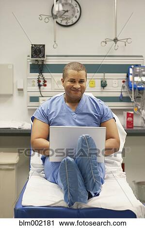 Stock Image - Mixed Race male medical professional typing on laptop. Fotosearch