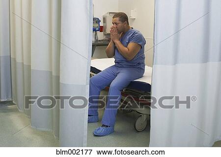 Stock Photo - Mixed Race male medical professional with hands on face. Fotosearch