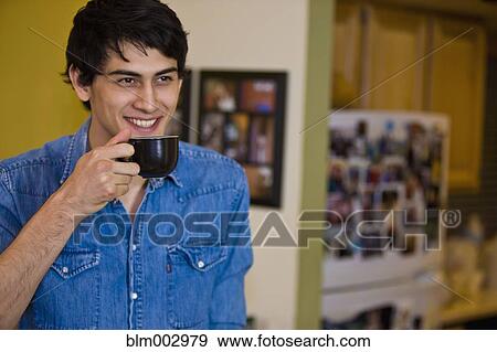 Mixed race man drinking coffee in kitchen View Large Photo Image Stock Photo - Mixed race man drinking coffee in kitchen. Fotosearch