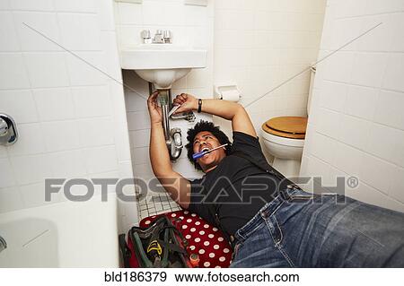 Mixed race man fixing sink plumbing View Large Photo Image Stock Photo - Mixed race man fixing sink plumbing. Fotosearch