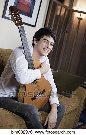 Stock Photograph - Mixed race man holding guitar. Fotosearch