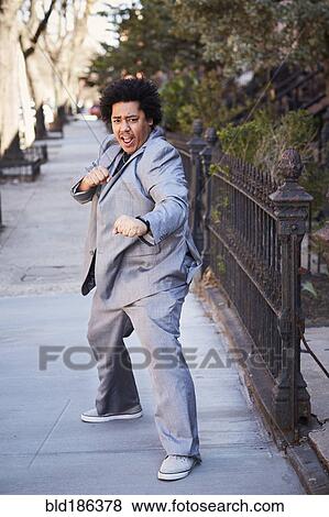 Stock Photo - Mixed race man in defensive pose on sidewalk. Fotosearch