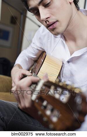 Stock Photography - Mixed race man playing guitar. Fotosearch