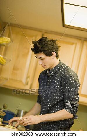 Stock Image - Mixed race man preparing food in kitchen. Fotosearch