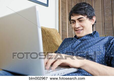 Stock Photo - Mixed race man typing on laptop. Fotosearch