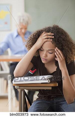 Stock Image - Mixed race student reviewing notes in classroom. Fotosearch