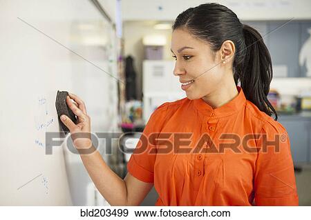 Mixed race teacher cleaning whiteboard in classroom View Large Photo Image Stock Photo - Mixed race teacher cleaning whiteboard in classroom. Fotosearch