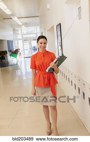 Mixed race teacher holding clipboard in school hallway View Large Photo Image Stock Photo - Mixed race teacher holding clipboard in school hallway. Fotosearch