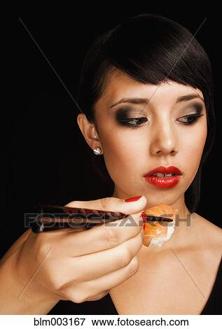 Stock Photo - Mixed race teenage girl eating sushi. Fotosearch