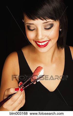 Stock Photo - Mixed race teenage girl eating sushi. Fotosearch