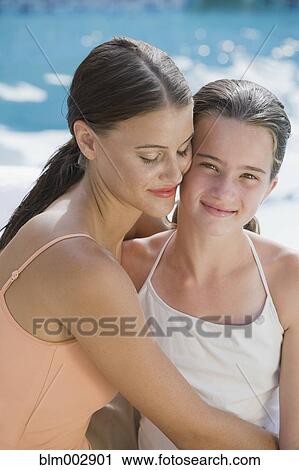 Stock Image - Mixed race woman and daughter in bathing suits hugging. Fotosearch
