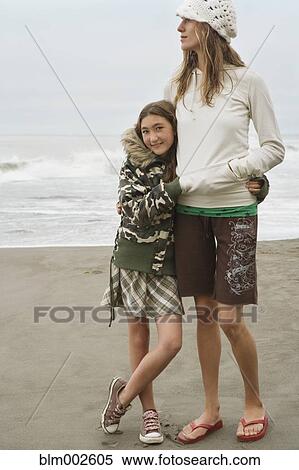 Stock Photography - Mixed race woman and sister hugging at beach. Fotosearch