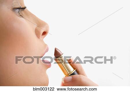 Stock Image - Mixed race woman applying lipstick. Fotosearch